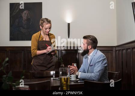 Serveuse prenant la commande du client au restaurant Banque D'Images