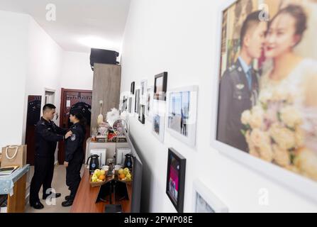 (230501) -- passe ALATAW, 1 mai 2023 (Xinhua) -- Cui Hongwu (L) aide Liu Xin à ranger son uniforme à la maison, dans le col Alataw, dans la région autonome de Xinjiang, dans le nord-ouest de la Chine, dans la province de 4 avril 2023. Le col Alataw est un important port terrestre situé à la frontière entre la Chine et le Kazakhstan, dans la région autonome du Xinjiang au nord-ouest de la Chine. CUI Hongwu, fonctionnaire de la station d'inspection frontalière du port, travaille depuis plus de 10 ans. Ici, il a rencontré sa femme Liu Xin, qui est son collègue et travaille comme maître de chien de police. Au cours des dernières années, le col Alataw a vu un nombre croissant et une fréquence accélérée de i Banque D'Images