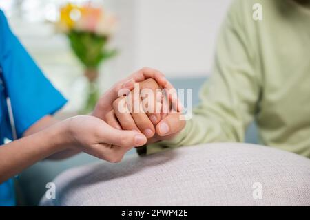 Journée internationale des personnes âgées. Une infirmière soignante qui aide l'établissement de soins pour personnes âgées reçoit de l'aide de l'hôpital, une jeune femme qui aide les mains pour lui offrir Banque D'Images