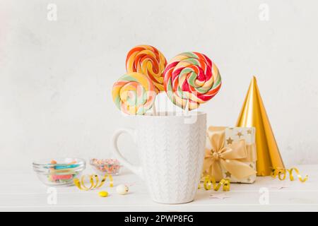 Bonbons colorés dans une tasse sur une table sur fond clair. Grands sucettes tournantes. Concept créatif d'un pot rempli de délicieux bonbons de la Banque D'Images