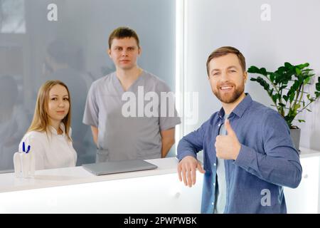 Patient reconnaissant. Homme debout à la réception de la clinique dentaire et très heureux pour le traitement Banque D'Images