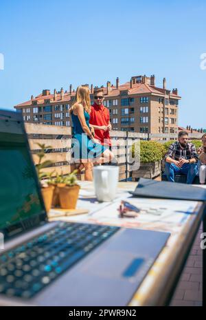 Couple parlant en pause-café sur le toit du bureau à côté de leurs collègues Banque D'Images