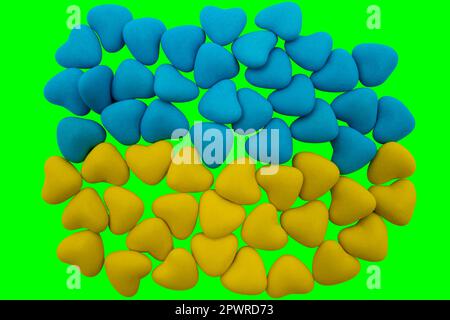 Bonbons jaunes et bleus en forme de coeur disposés sous la forme du drapeau national de l'Ukraine sur fond vert (clé chromique). Gros plan, vue de dessus Banque D'Images