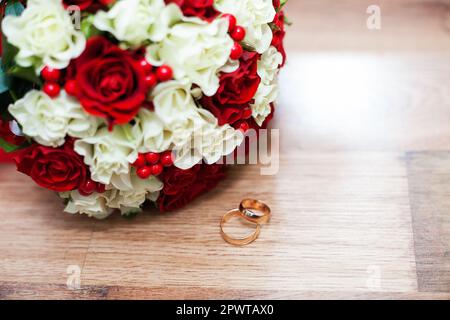 Bagues et un mariage bouquet de roses rouges et blanches sur une table Banque D'Images