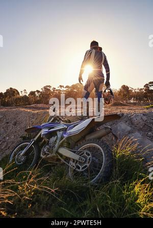 C'était une promenade trépidante. Vue arrière d'un motocross pilote debout devant sa moto. Banque D'Images