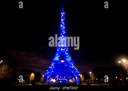 L'emblématique Tour Eiffel illuminée la nuit, tour en treillis de fer forgé de Paris, France, arrière-plan effet bokeh défoqué. Banque D'Images
