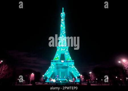 L'emblématique Tour Eiffel illuminée la nuit, tour en treillis de fer forgé de Paris, France, arrière-plan effet bokeh défoqué. Banque D'Images