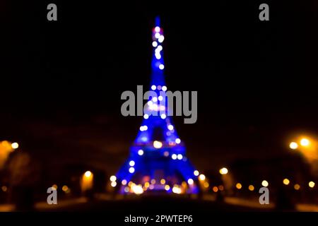 L'emblématique Tour Eiffel illuminée la nuit, tour en treillis de fer forgé de Paris, France, arrière-plan effet bokeh défoqué. Banque D'Images