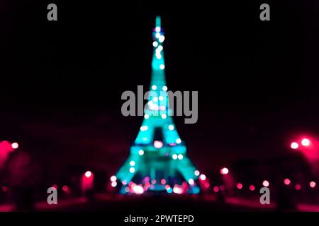 L'emblématique Tour Eiffel illuminée la nuit, tour en treillis de fer forgé de Paris, France, arrière-plan effet bokeh défoqué. Banque D'Images