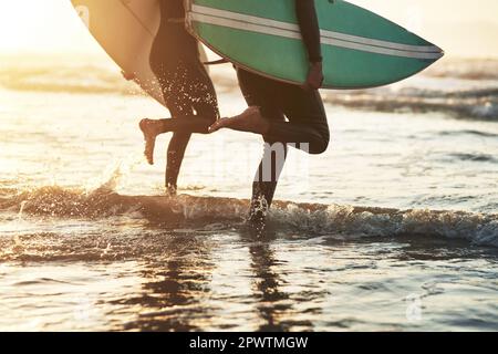 Nous trouvons la liberté dans les eaux qui font rage. un jeune couple méconnaissable qui fait du surf à la plage Banque D'Images