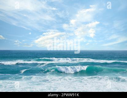 Vue panoramique sur les vagues se déroulant sur le bord de mer contre un ciel bleu ciel nuageux en été. Vue pittoresque et paisible sur une plage d'eau claire dans une atmosphère tropicale Banque D'Images