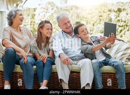 Un autre selfie pour le réfrigérateur de grand-Noël. un jeune garçon utilisant une tablette numérique tout en étant assis à la maison avec sa sœur et ses grands-parents Banque D'Images