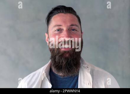 portrait d'un homme barbu souriant et regardant avec confiance l'appareil photo Banque D'Images