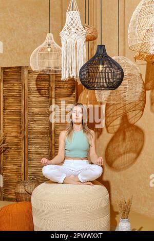 Yoga pour les personnes âgées. Femme qui se balance sur un tabouret rembourré dans la posture du lotus. Banque D'Images