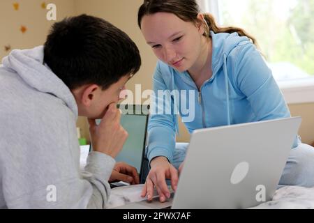 résoudre le problème de l'ordinateur portable adolescents garçon fille penchée au-dessus de l'ordinateur portable regardant les uns les autres résoudre les problèmes faire devoirs enfants apprendre ensemble en ligne cours d'anglais aider avec les devoirs amitié Banque D'Images