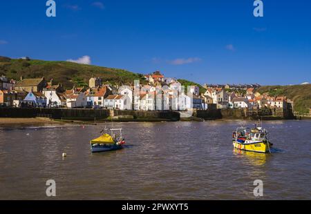 Vue sur le port de Staithes à marée haute.deux petits bateaux de pêche sont amarrés au milieu du port. Banque D'Images