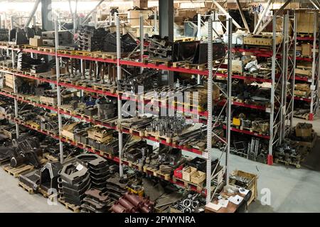 Partie d'une grande salle de stockage ou d'un entrepôt d'usine industrielle avec des rangées de grands racks avec pièces de rechange et détails pour les machines sur des étagères Banque D'Images