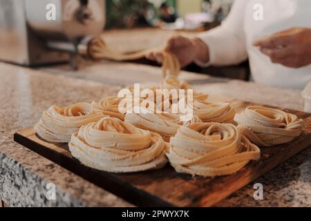 Délicieuses pâtes de tagliatelle crues sur planche à découper en bois Banque D'Images