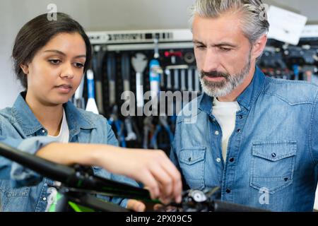 La femme et l'homme comme la mécanique de vélo dans la préparation de l'atelier Banque D'Images