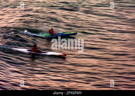 Canoë au coucher du soleil dans la mer de la ville de Salvador à Bahia avec des mouvements flous et des gens méconnaissables Banque D'Images