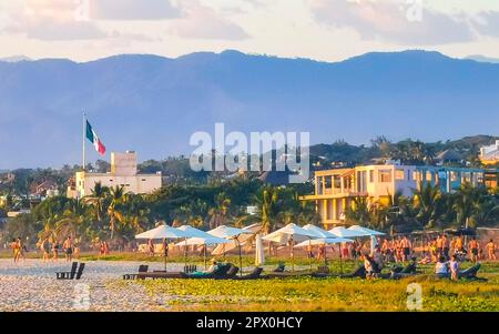 Puerto Escondido Oaxaca Mexique 02. Décembre 2022 les gens regardent magnifique coucher de soleil coloré et doré dans le rouge orange jaune sur la plage et b Banque D'Images