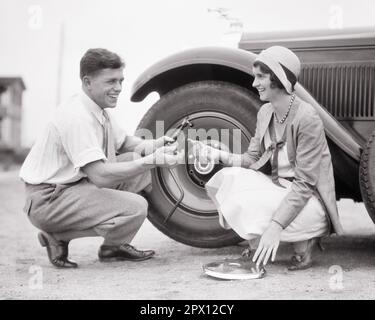 1920S COUPLE SOURIANT HOMME ET FEMME TRAVAILLANT ENSEMBLE POUR CHANGER LA ROUE AVEC PNEU À PLAT SUR L'AUTOMOBILE - M3418 HAR001 HARS TRAVAIL D'ÉQUIPE HEUREUX JOIE STYLE DE VIE SATISFACTION FEMMES MARIÉ RURAL CHANGEMENT CONJOINT ÉPOUX PNEU COPIE ESPACE PLAT AMITIÉ PLEINE LONGUEUR FEMMES PERSONNES AUTOMOBILE LES HOMMES RISQUENT CONFIANCE TRANSPORT PARTENAIRE B&W RÉUSSITE CATASTROPHE JOYEUSE ET PROGRÈS DE LA CONNAISSANCE SUR L'OCCASION DE SOURIRE CONCEPTUEL JOYEUX SOUTIEN ÉLÉGANT HOMME MOYEN-ADULTE HOMME MOYEN-ADULTE SOLUTION FEMME MOYEN-ADULTE FEMMES DE TOGETHERNESS NOIR ET BLANC RACE BLANCHE HAR001 OLD FASHIONED Banque D'Images