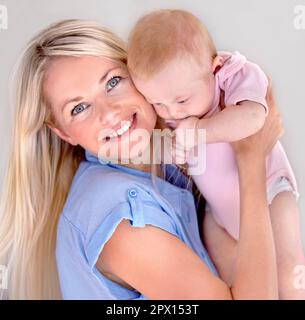 Shes ma petite princesse. Jeune mère souriant largement tout en tenant son bébé près. Banque D'Images