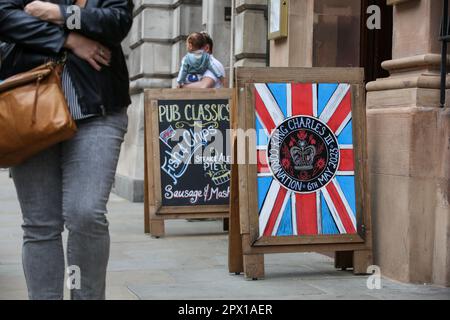 Londres, Royaume-Uni. 01st mai 2023. Une femme passe devant un panneau Union Jack à l'extérieur d'un pub à Westminster, dans le centre de Londres, alors que les préparatifs pour le couronnement du roi Charles III se poursuivent. Le couronnement du roi Charles III et de la reine Camilla aura lieu sur 6 mai avec des dizaines de milliers de personnes du monde entier qui devraient suivre la route entre le palais de Buckingham et l'abbaye de Westminster dans le centre de Londres. Crédit : SOPA Images Limited/Alamy Live News Banque D'Images