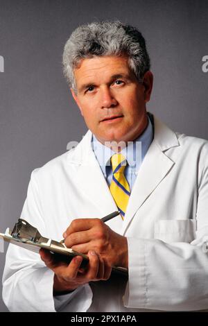 1990S PORTRAIT HOMME MÉDECIN PORTANT UNE BLOUSE DE LABORATOIRE BLANCHE ÉCRIRE SUR LE PRESSE-PAPIERS AVEC UNE EXPRESSION SÉRIEUSE MAIS AMICALE REGARDANT LA CAMÉRA - KM9613 BAR007 HARS SOINS ATTENTIONNÉS HOMMES PROFESSION D'ÂGE MOYEN HOMME D'ÂGE MOYEN CONTACT OCULAIRE SOINS DE SANTÉ PROFESSION FOURNISSEURS DE SERVICES DE PRÉVENTION PRATICIENS GUÉRISON DIAGNOSTIC CARRIÈRES MÉDECINS TROUBLES DE LA SANTÉ PROFESSIONS TRAITEMENT GUÉRISSEUR AMICAL MÉDECIN PRATICIEN SINCÈRE SOLENNEL FOCALISÉ PROFESSIONNELS INTENSES SOLUTIONS SOIGNEUX CAUCASIEN LA MALADIE ETHNIQUE EST UNE INTENTION SINCÈRE À L'ANCIENNE Banque D'Images