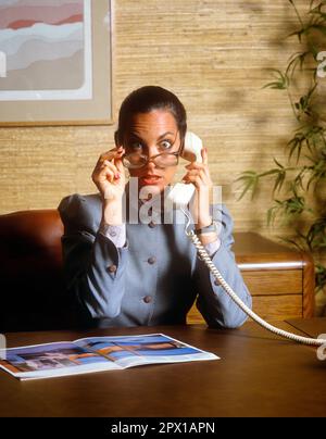 1980S FEMME D'AFFAIRES SUR APPEL TÉLÉPHONIQUE ASSIS AU BUREAU A CHOQUÉ L'EXPRESSION FACIALE REGARDANT PAR-DESSUS LES YEUX DE LUNETTES GRAND OUVERT - KO1449 TEU001 HARS SILLY FACIAL PEUR COMMUNICATION CHOC CHOQUÉ COMIC INFORMATION MYSTÈRE STYLE DE VIE APPEL FEMMES EMPLOIS COMMUNICATION MANAGER COPIE ESPACE DEMI-LONGUEUR FEMMES PERSONNES CADRES LUNETTES STUPÉFAIT FEMME D'AFFAIRES GRAND OEIL COMPÉTENCES DE CONTACT WONDER BUG-EYED AWE HUMOUR COMPÉTENCES D'OCCUPATION EXCITATION COMIQUE OCCUPATIONS TÉLÉPHONES PATRONS CONCEPTUELS TÉLÉPHONES BRASIER LA COMÉDIE STARTLE FEMMES D'AFFAIRES STUN ÉTRIQUÉ ÉTRIEUX CADRES ÉTONNAMMENT ÉTRIQUÉS CAUCASIENS ETHNICITÉ ANCIEN MODE Banque D'Images