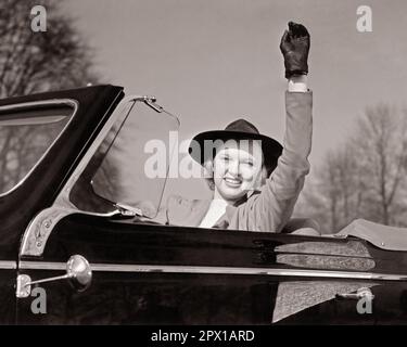 1930S BLONDE FEMME SOURIANTE CONDUITE CABRIOLET BRAS RELEVÉ AGITANT UN SALUT - M1010 HAR001 HARS ÉLEVÉ HEUREUX JOIE STYLE DE VIE FEMMES SANTÉ COPIE ESPACE AMITIÉ FEMMES PERSONNES AUTOMOBILE CONFIANCE TRANSPORT B&W BONHEUR TÊTE ET ÉPAULES GAIES AVENTURE STYLES AUTOS EXCITATION BAS ANGLE FIERTÉ SOURIT AUTOMOBILES JOYEUSE VÉHICULES STYLÉS MODE JEUNE FEMME ADULTE NOIR ET BLANC CAUCASIEN ETHNICITÉ HAR001 VIEUX MODE Banque D'Images