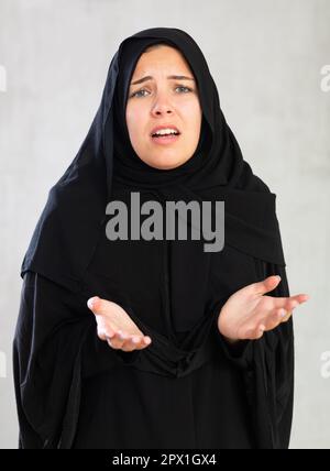 Une jeune femme inquiète vêtue de vêtements islamiques traditionnels Banque D'Images