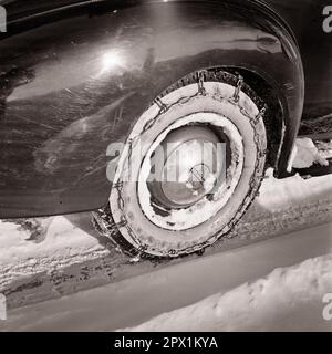 1930S GROS PLAN DES CHAÎNES À NEIGE SUR LE PNEU D'UNE VOITURE OLDSMOBILE OFFRANT UNE MEILLEURE TRACTION LORS DE LA CONDUITE DANS LA NEIGE ET LA GLACE D'HIVER - M6370 HAR001 HARS DÉMODÉE Banque D'Images