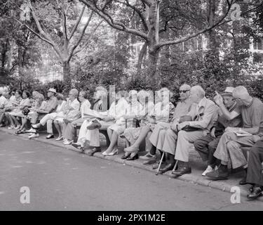 1970S LONG BANC DANS LE PARC DE LA VILLE AVEC TOUS LES HOMMES ET FEMMES ÂGÉS ASSIS À L'EXCEPTION D'UN HOMME PLUS JEUNE - S21144 HAR001 HARS ÉTATS-UNIS COPIE ESPACE AMITIÉ DEMI-LONGUEUR DAMES PERSONNES ÉTATS-UNIS D'AMÉRIQUE HOMMES RETRAITE HOMME ÂGÉ SENIOR ADULTE B&W ÉTÉ SENIOR FEMME RETRAITÉ ANCIEN ÂGE OLDSTERS OLDSTER LOISIRS CANNES ET VIEILLISSEMENT OPPORTUNITÉ DE LOISIRS NYC ANCIENS CONNEXION LES RETRAITÉS DES VILLES CONCEPTUELLES DE NEW YORK SOUTIENNENT LA COOPÉRATION PANORAMIQUE DE LA VILLE DE NEW YORK SAISON DE RELAXATION ENSEMBLE JEUNE RACE BLANCHE ET NOIRE HAR001 DÉMODÉE Banque D'Images