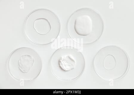 Différents produits cosmétiques échantillons de gel dans des boîtes de Petri de laboratoire sur fond blanc Banque D'Images