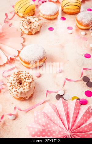 Berliner traditionnel pour le carnaval et la fête. Krapfen allemand ou beignets avec des banderoles et des confettis. Image de carnaval ou d'anniversaire colorée Banque D'Images