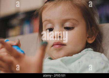 Bébé fille dessin sur sa main avec un marqueur bleu. Le concept de la créativité des enfants. Peinture sale pour bébé Banque D'Images
