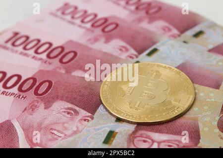 Bitcoin placé sur le dessus d'une centaine de milliers de rupias billet de banque. Concept de trading de crypto-monnaie Banque D'Images