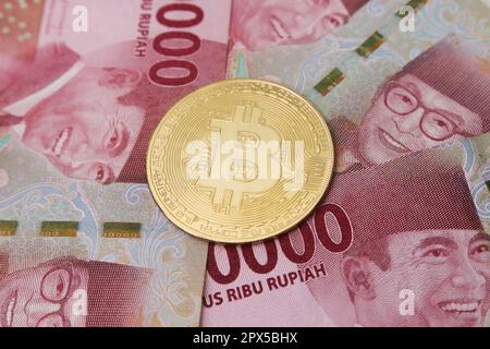 Bitcoin placé sur le dessus d'une centaine de milliers de rupias billet de banque. Concept de trading de crypto-monnaie Banque D'Images