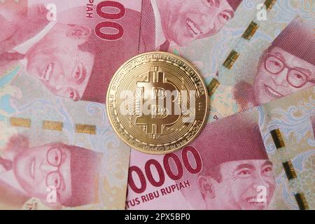 Bitcoin placé sur le dessus d'une centaine de milliers de rupias billet de banque. Concept de trading de crypto-monnaie Banque D'Images