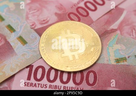 Bitcoin placé sur le dessus d'une centaine de milliers de rupias billet de banque. Concept de trading de crypto-monnaie Banque D'Images