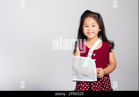 Bras cassé. Petit mignon enfant fille de 3-4 ans os de main cassé d'accident avec attelle de bras dans le studio de tir isolé sur fond blanc, enfant asiatique Banque D'Images