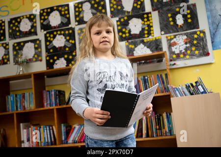 Wardenburg, Allemagne. 28th avril 2023. Ansitasia Savenko est debout dans son école avec un livre en bas allemand. Il y a un an, l'enfant de neuf ans a fui l'Ukraine avec sa famille vers l'Allemagne. Elle représentera son école au niveau du district dans le concours de lecture 2023 de l'Oldenburgische Landschaft de 29th. (À dpa 'réfugié de neuf ans concurrence dans la compétition de lecture de bas allemand') Credit: Sina Schuldt/dpa/Alay Live News Banque D'Images