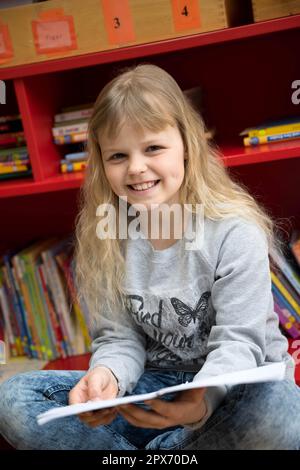 Wardenburg, Allemagne. 28th avril 2023. Ansitasia Savenko est assise dans son école avec un livre en bas allemand. Il y a un an, l'enfant de neuf ans a fui l'Ukraine avec sa famille vers l'Allemagne. Elle représentera son école au niveau du district dans le concours de lecture 2023 de l'Oldenburgische Landschaft en 29th. (À dpa 'réfugié de neuf ans concurrence dans la compétition de lecture de bas allemand') Credit: Sina Schuldt/dpa/Alay Live News Banque D'Images