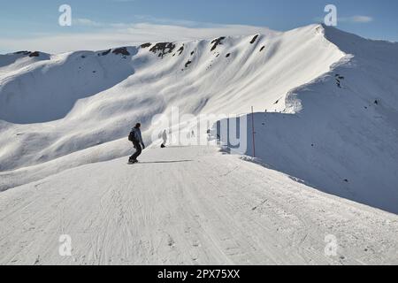 Vue sur les pistes de ski dans les Alpes, skieurs méconnus sur la piste de ski le long d'une crête Banque D'Images