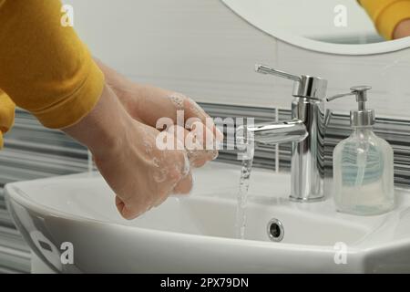 Homme se lavant les mains avec du savon dans le lavabo de la salle de bains, gros plan Banque D'Images