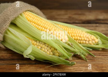 Cornons frais avec des huttes vertes sur une table en bois, gros plan Banque D'Images