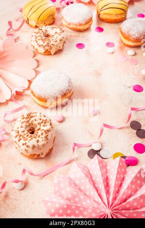 Berliner traditionnel pour le carnaval et la fête. Krapfen allemand ou beignets avec des banderoles et des confettis. Image de carnaval ou d'anniversaire colorée Banque D'Images