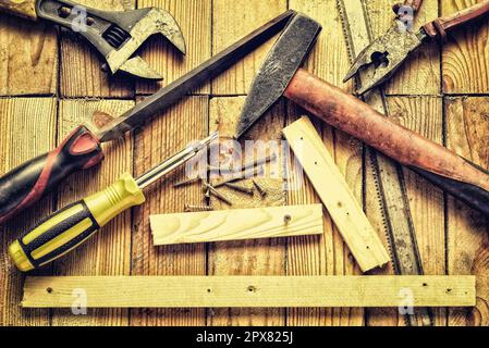 Outils de rénovation de style vintage. Marteau, lime plate, pince, tournevis, clé à singe, vis, planches et lame sur fond en bois naturel. Banque D'Images