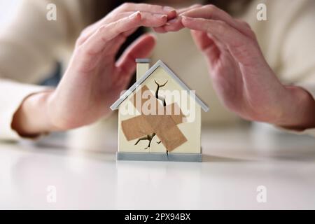 Femme d'affaires protégeant la maison brisée. Dommages immobiliers Banque D'Images